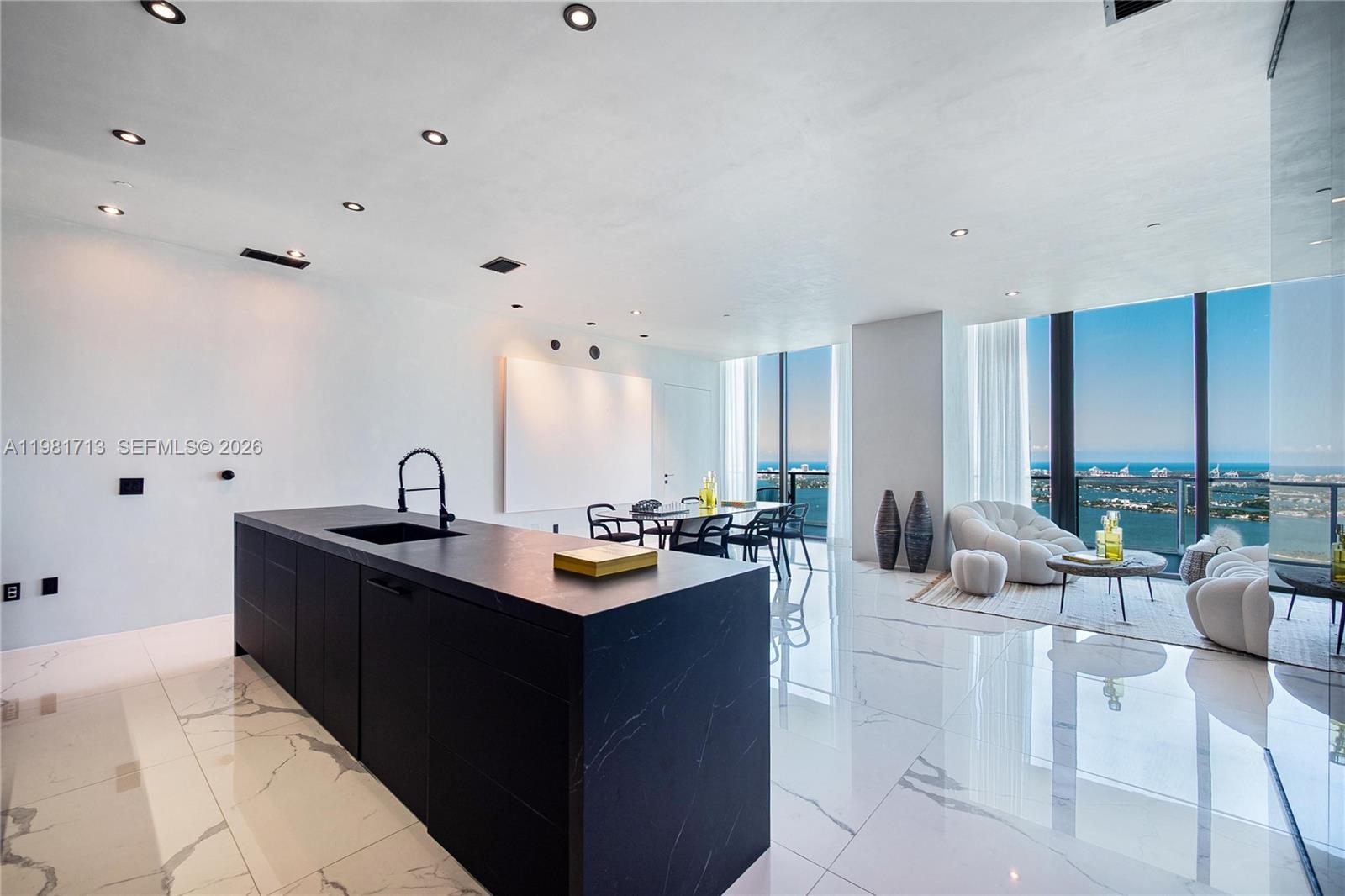 A modern kitchen and living area feature a black island, marble floors, and floor-to-ceiling windows — 650 NE 32nd St, Miami FL 33137, MIAMI, FL