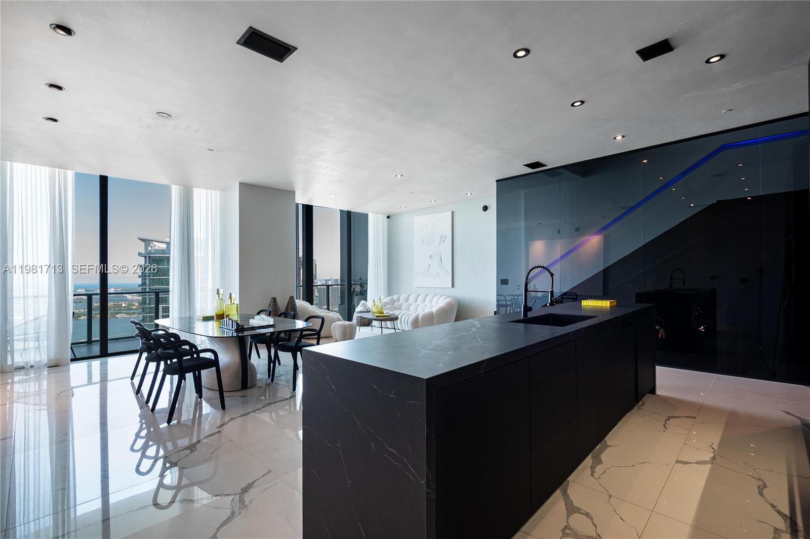 A modern kitchen and dining area features a black marble island and white tile floors — 650 NE 32nd St, Miami FL 33137, MIAMI, FL