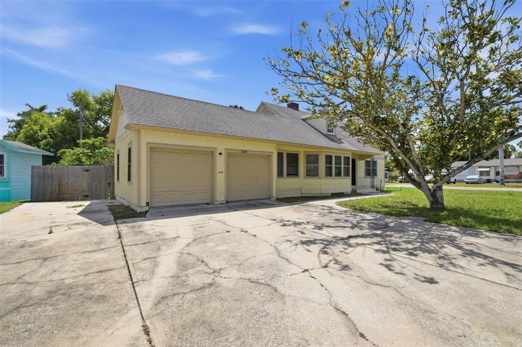A yellow house with a two-car garage and a cracked concrete driveway — 2513 16TH AVENUE W, BRADENTON, FL