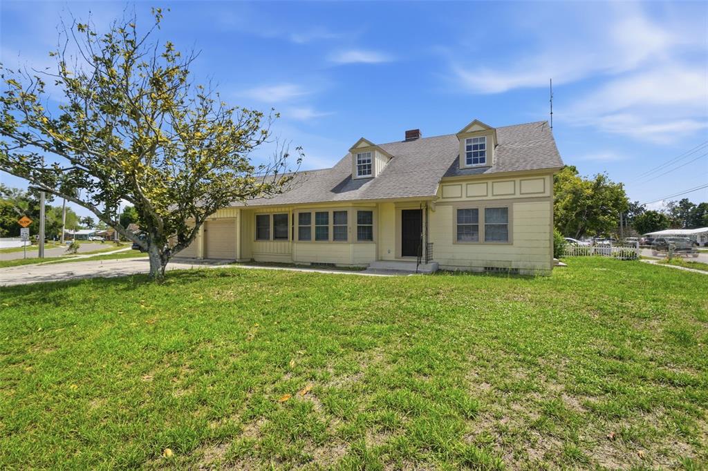 A yellow, two-story house with a gabled roof and dormer windows sits on a lawn — 2513 16TH AVENUE W, BRADENTON, FL