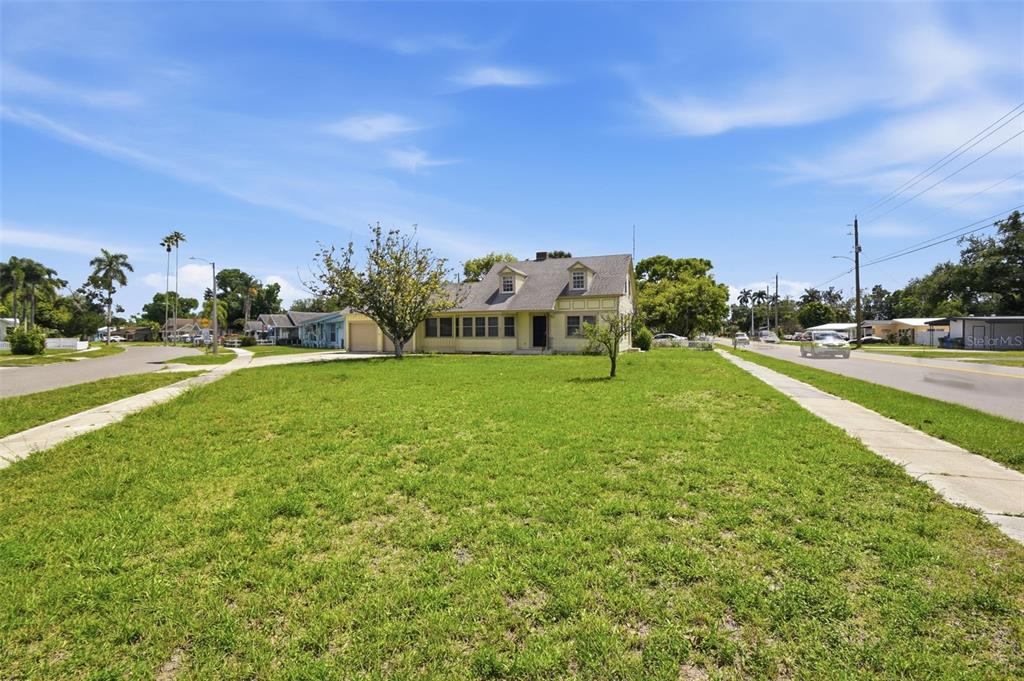 A yellow house with a large front lawn sits on a corner lot — 2513 16TH AVENUE W, BRADENTON, FL