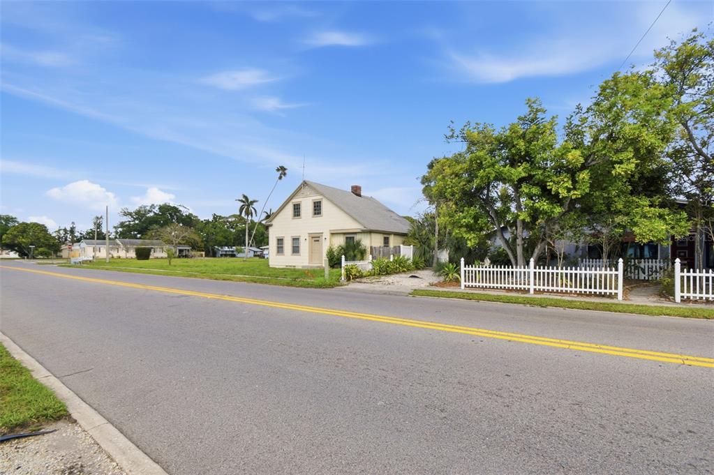 A light-colored, two-story house sits beside a road with a white picket fence — 2513 16TH AVENUE W, BRADENTON, FL