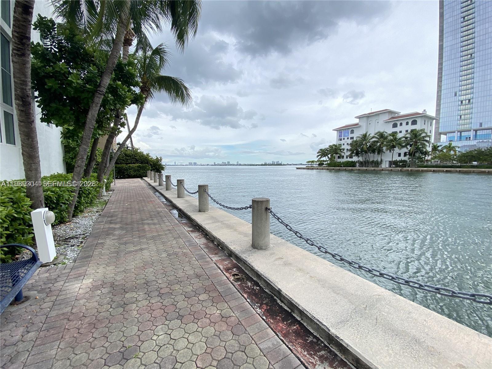 A paved walkway runs alongside a waterfront bulkhead with concrete posts and chain railings — 500 NE 29th St # 608, Miami FL 33137, MIAMI, FL