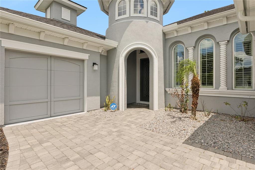 A gray house exterior features a paved driveway, a garage, and an arched entryway — 2423 WILD TURKEY CREEK LANE, PORT ORANGE, FL