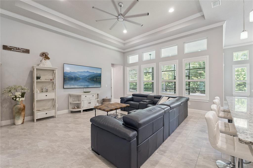 A spacious living room features a large sectional sofa, a wall-mounted television, and tile flooring — 2423 WILD TURKEY CREEK LANE, PORT ORANGE, FL