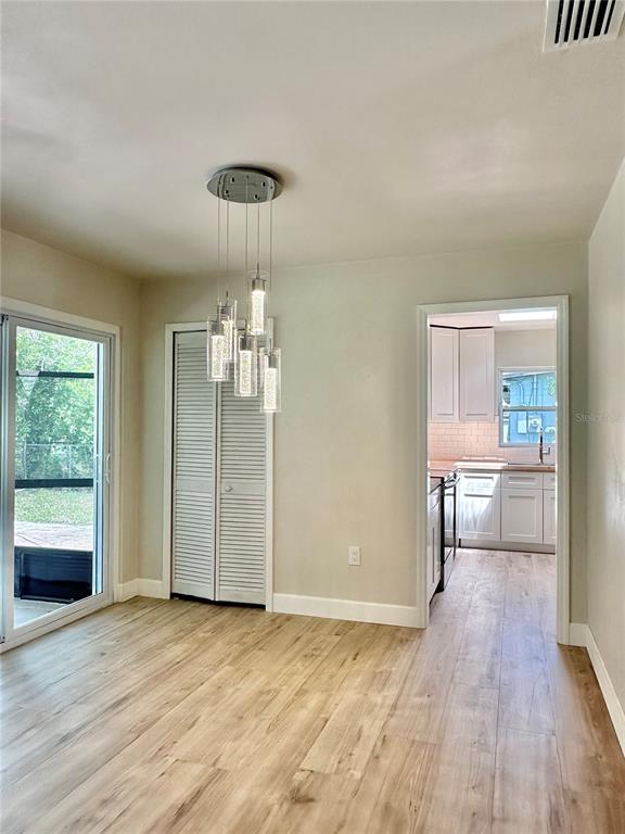 A dining area features light wood-look flooring, a modern pendant light, and a kitchen view — 400 DALTON BOULEVARD, PORT CHARLOTTE, FL