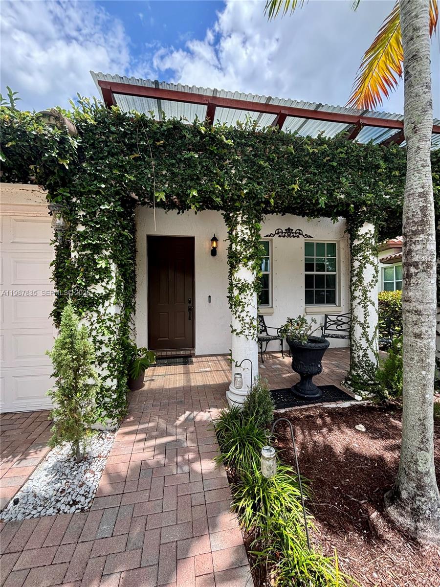 A brick walkway leads to a covered front porch with climbing vines on white columns — 8080 NW 126th Ter, Parkland FL 33076, PARKLAND, FL