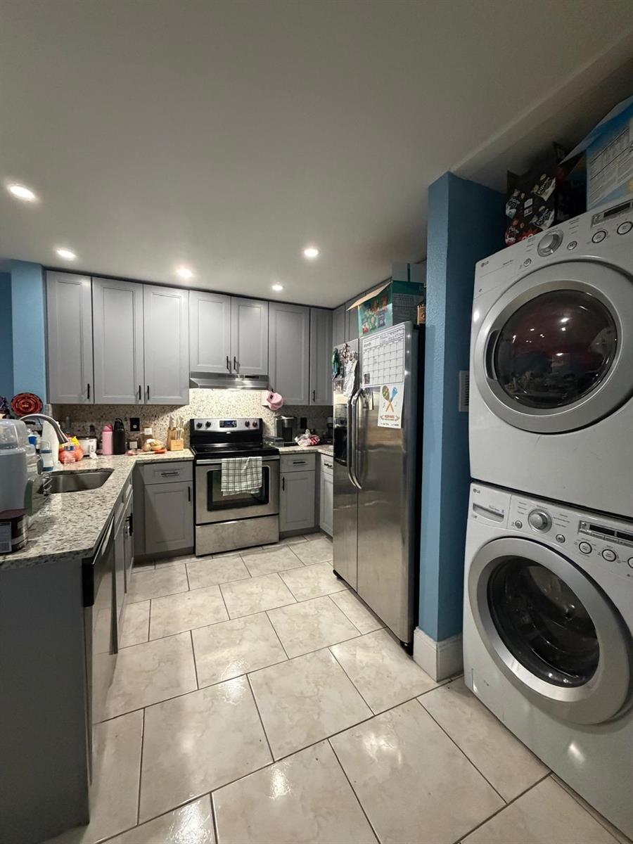 A kitchen with gray cabinets, granite countertops, stainless steel appliances, and a stacked laundry unit — 5362 SW 125th Avenue, Miramar FL 33027, MIRAMAR, FL