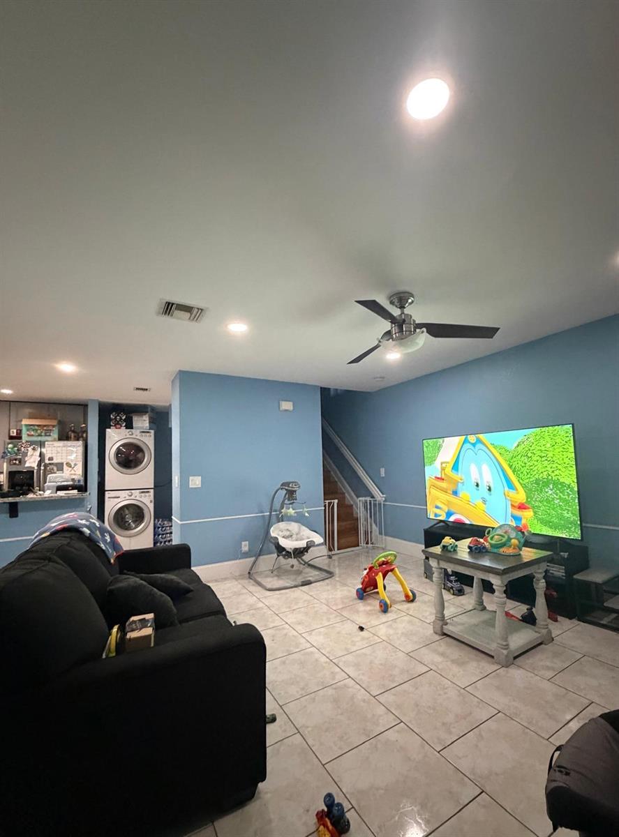 A living room with blue walls, tile flooring, a black sofa, and a television — 5362 SW 125th Avenue, Miramar FL 33027, MIRAMAR, FL