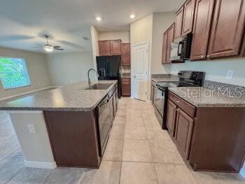 A kitchen features dark wood cabinets, granite countertops, a center island, and tile flooring — 17132 WHITE MANGROVE DRIVE, WIMAUMA, FL