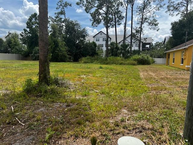A grassy vacant lot sits in front of a multi-story building and trees — IOWA STREET, DAYTONA BEACH, FL
