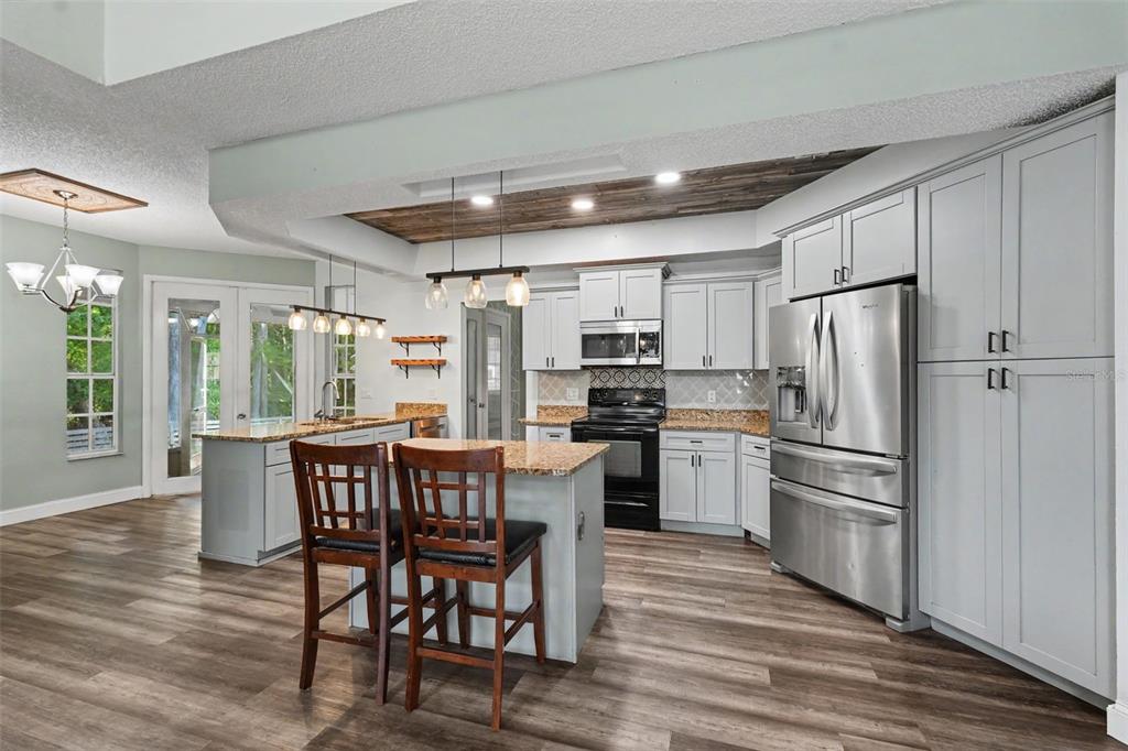 A kitchen features light gray cabinets, granite countertops, stainless steel appliances, and wood-look flooring — 10551 CASEY DRIVE, NEW PORT RICHEY, FL