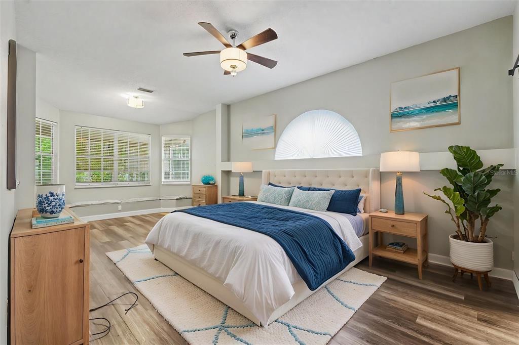 A bedroom features a bed with blue bedding, a ceiling fan, and a large window — 10551 CASEY DRIVE, NEW PORT RICHEY, FL