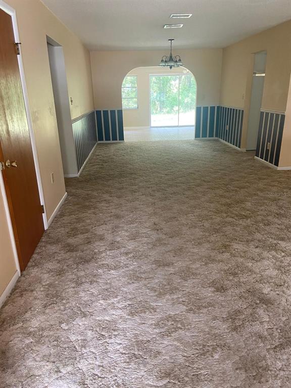 A carpeted living room features blue and white striped wainscoting and an arched entryway — 4059 S LINWOOD TERRACE, INVERNESS, FL