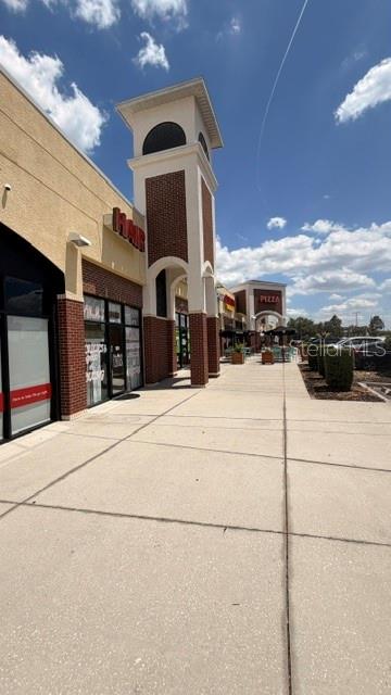 A view of a commercial shopping center sidewalk with a prominent brick and stucco tower — 42601 HIGHWAY 27, DAVENPORT, FL