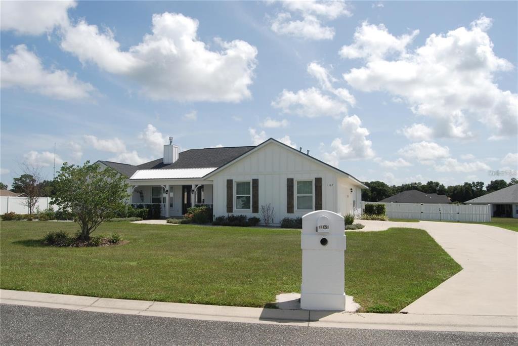 A white, single-story house with a metal roof, shutters, and a concrete driveway — 1167 SE 63RD COURT ROAD, OCALA, FL