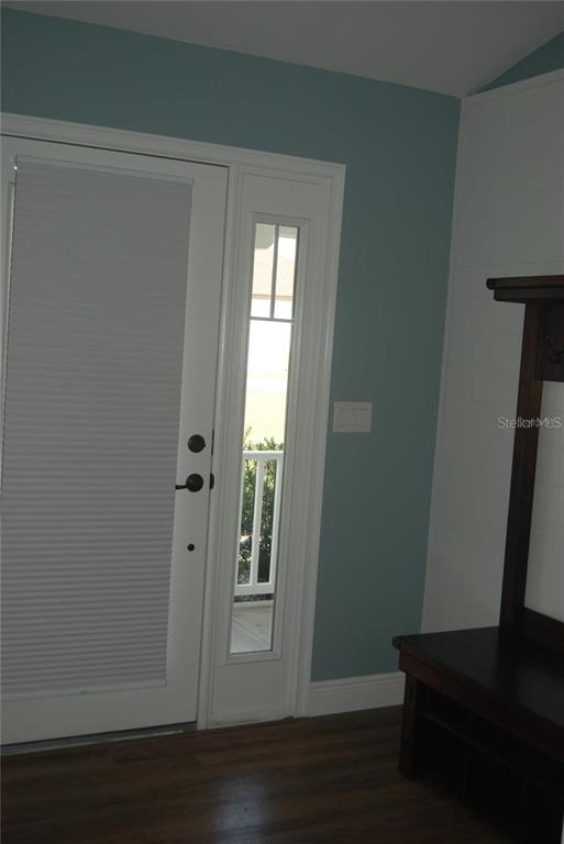 A white front door with a side window sits next to a dark wood entryway bench — 1167 SE 63RD COURT ROAD, OCALA, FL
