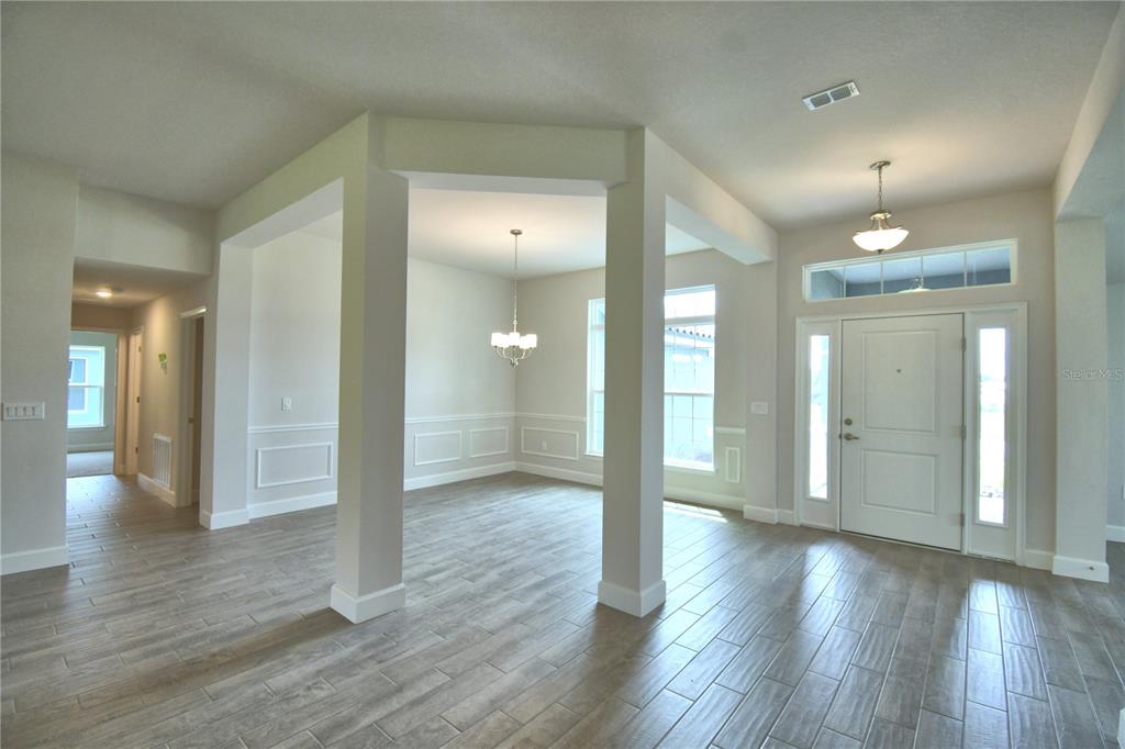 An entryway leads into a dining area featuring wood-look tile flooring and white trim — 5421 WATERSIDE DRIVE, AUBURNDALE, FL