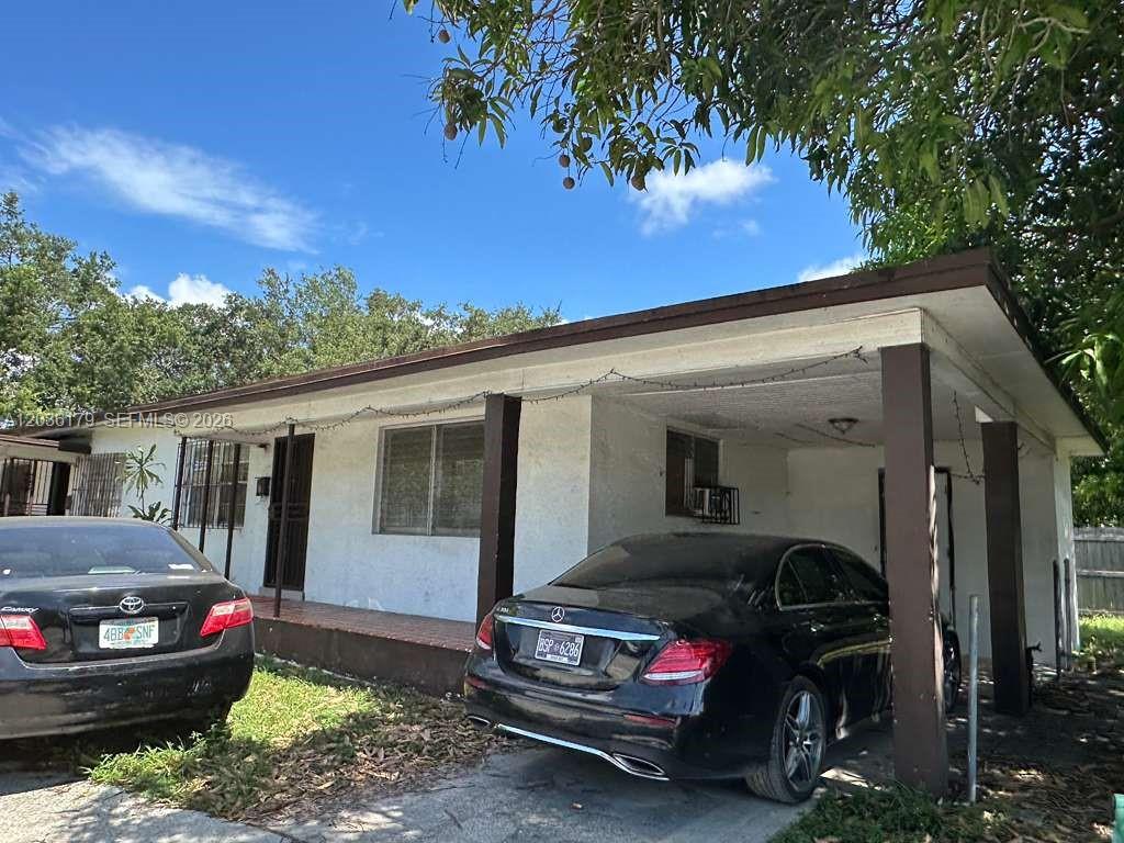 A single-story house with a carport and two parked cars under a blue sky — 545 NW 81st St, Miami FL 33150, MIAMI, FL