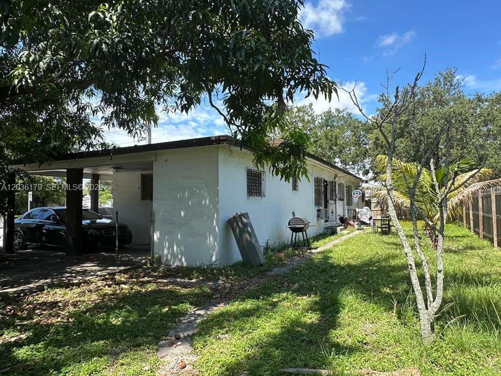 A white single-story house features a carport, a grassy yard, and a wooden fence — 545 NW 81st St, Miami FL 33150, MIAMI, FL