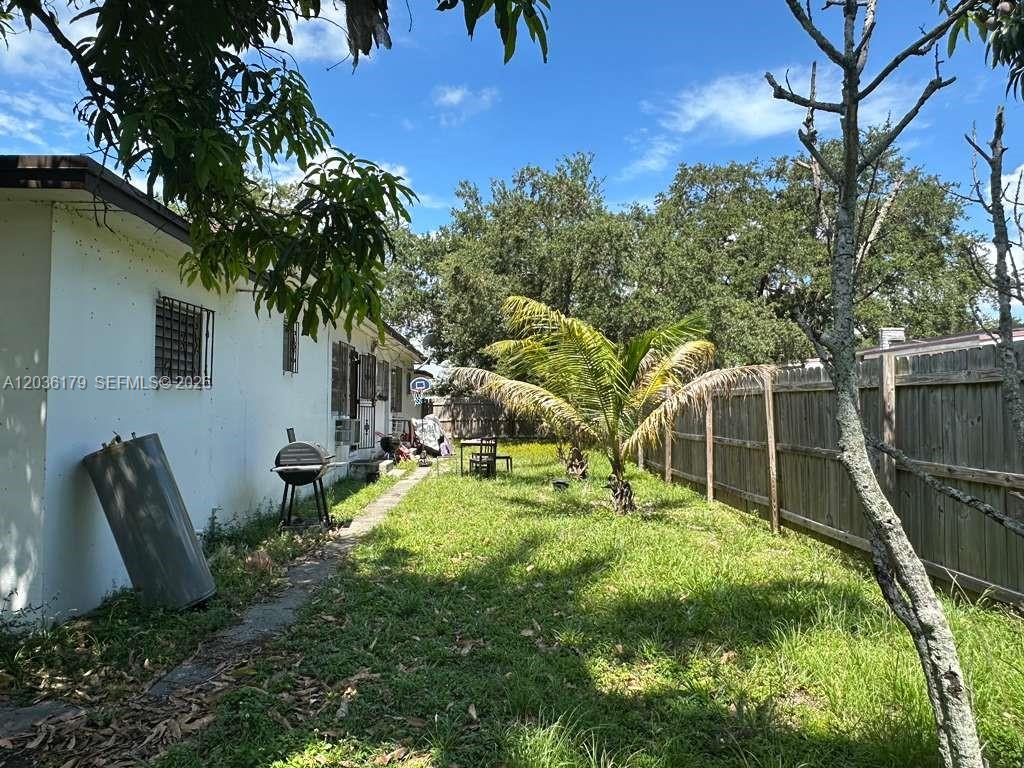 A backyard features a white house exterior, a grill, a palm tree, and a wooden fence — 545 NW 81st St, Miami FL 33150, MIAMI, FL