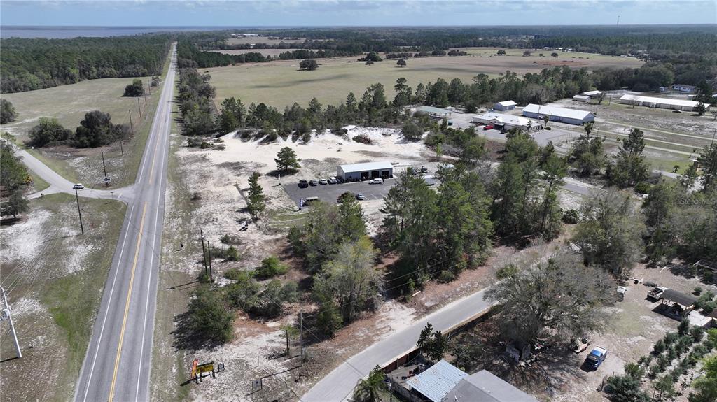 An aerial view shows a commercial building, parking lot, and surrounding land near a road — 106 SHRINE CLUB ROAD, POMONA PARK, FL
