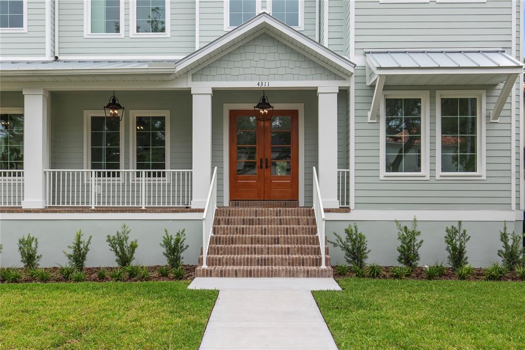 A light green house with a front porch, brick steps, and a wooden double door — 4311 W SEVILLA STREET, TAMPA, FL