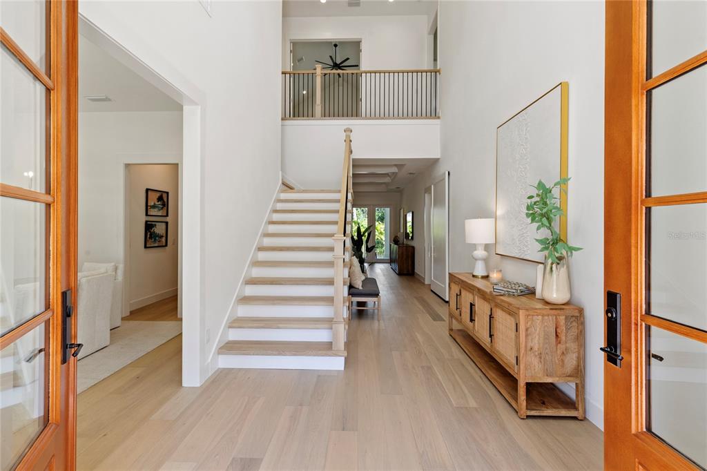 A bright foyer features light wood flooring, a staircase with white risers, and a wooden console — 4311 W SEVILLA STREET, TAMPA, FL