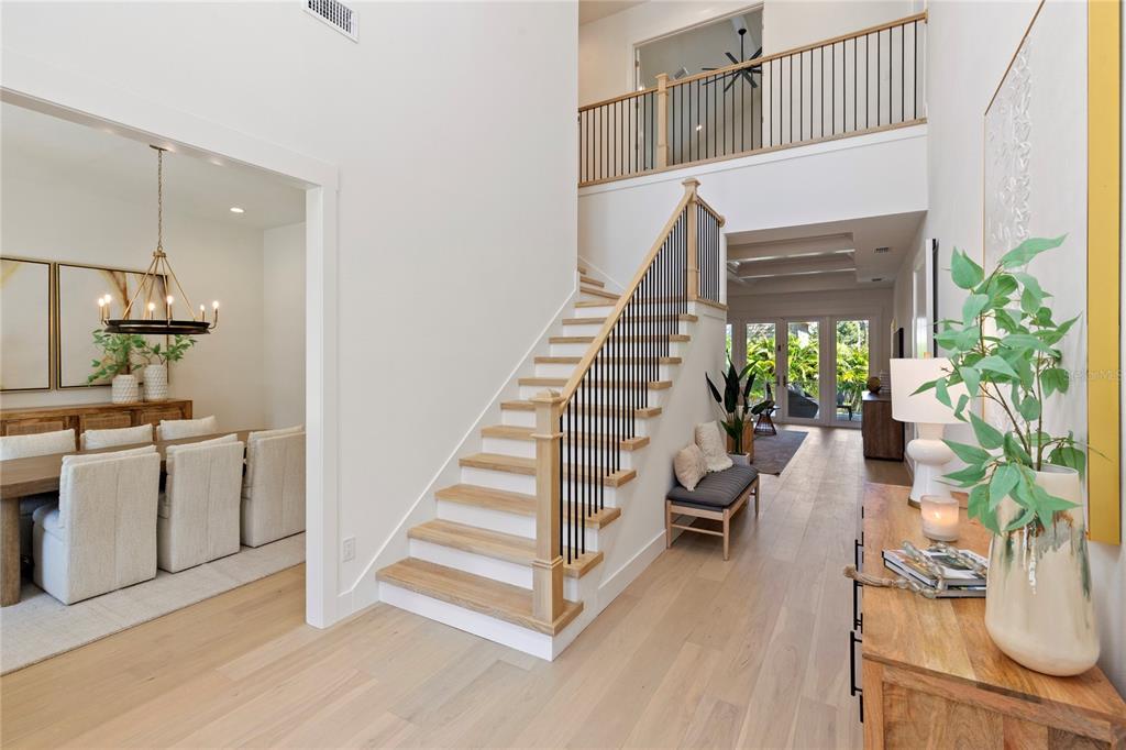 A bright entryway features light wood flooring, a staircase with black railings, and a dining area — 4311 W SEVILLA STREET, TAMPA, FL
