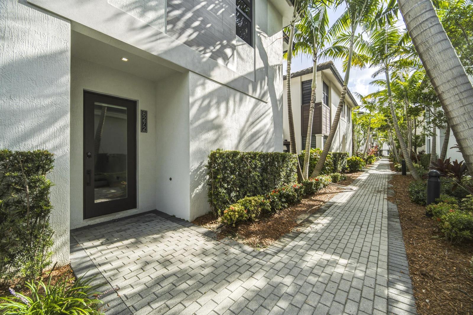 A paved walkway leads to the entrance of a modern white building with palm trees — 8272 NW 44th Terrace, Doral FL 33166, DORAL, FL