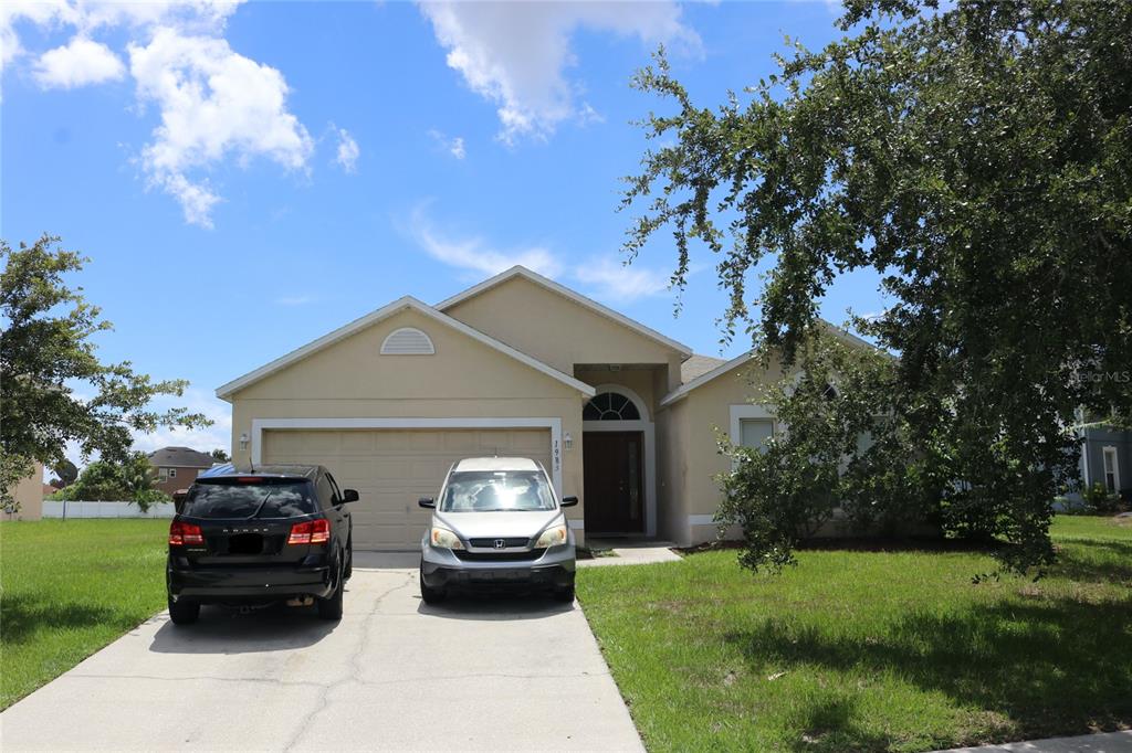 A single-story house with a two-car garage and two parked vehicles in the driveway — 1983 PERIDOT CIRCLE, KISSIMMEE, FL