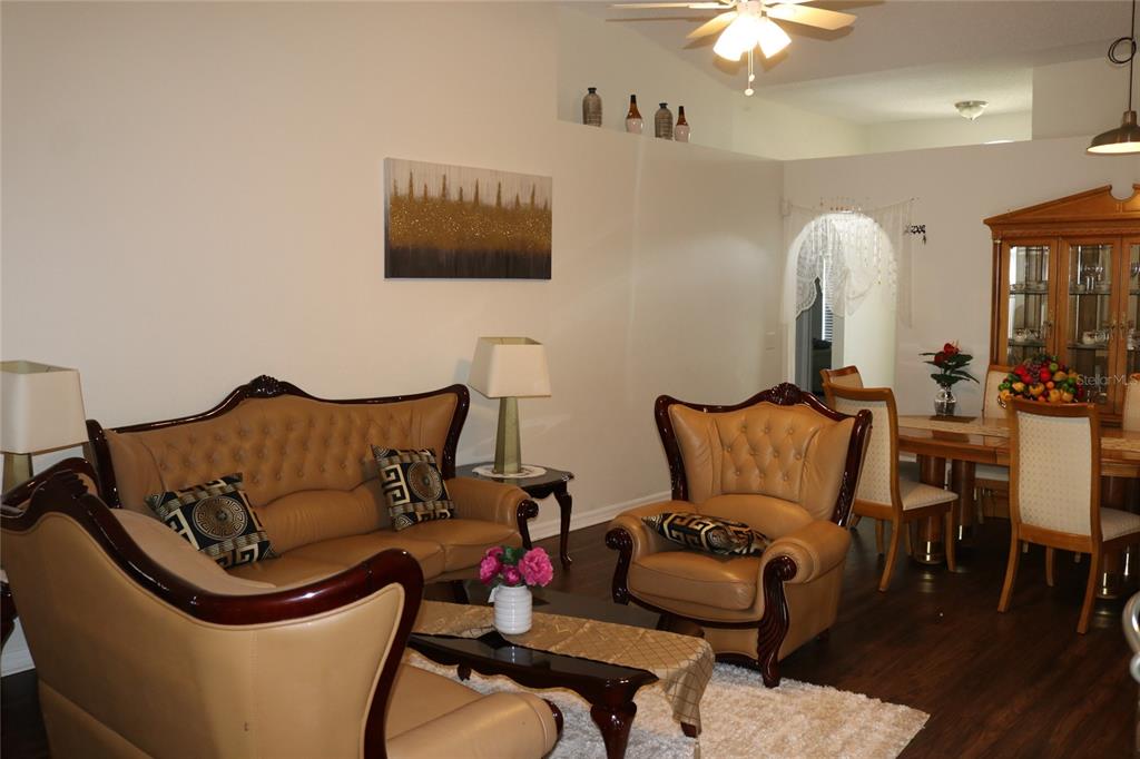 A living room features tan leather furniture, a dark wood coffee table, and dining area — 1983 PERIDOT CIRCLE, KISSIMMEE, FL