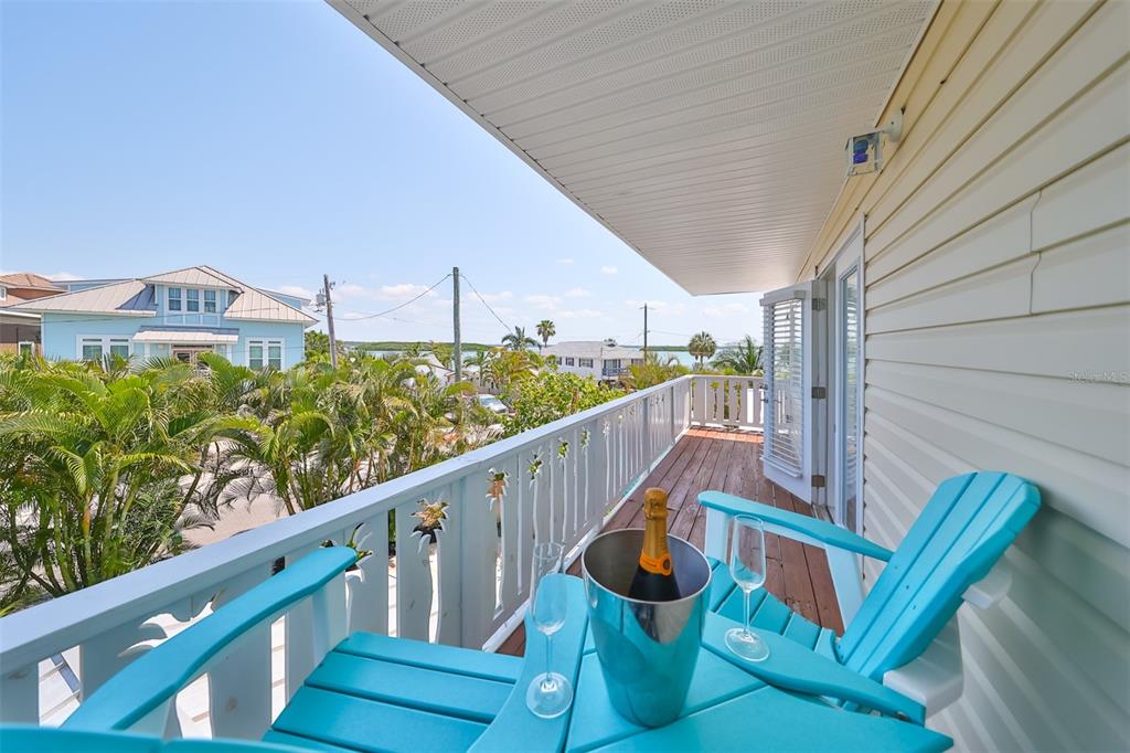 A balcony with two blue chairs, a champagne bucket, and a view of the water — 13004 BOCA CIEGA AVENUE, MADEIRA BEACH, FL