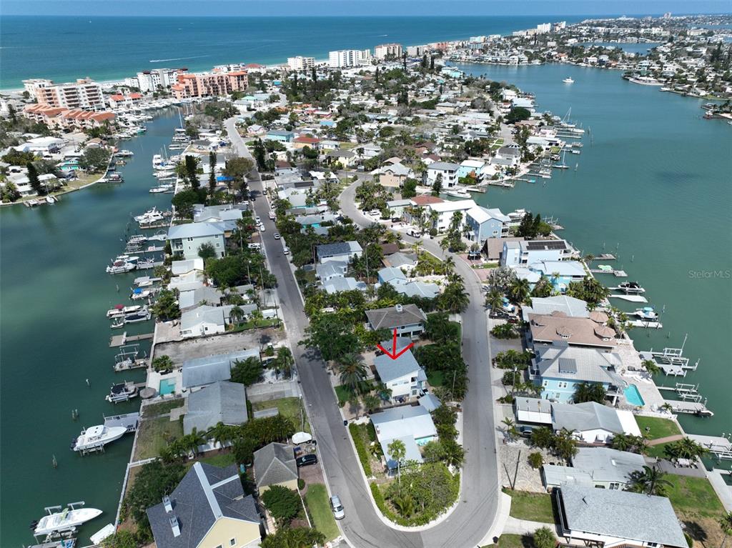 An aerial view shows a coastal neighborhood with houses, canals, and boats — 13004 BOCA CIEGA AVENUE, MADEIRA BEACH, FL