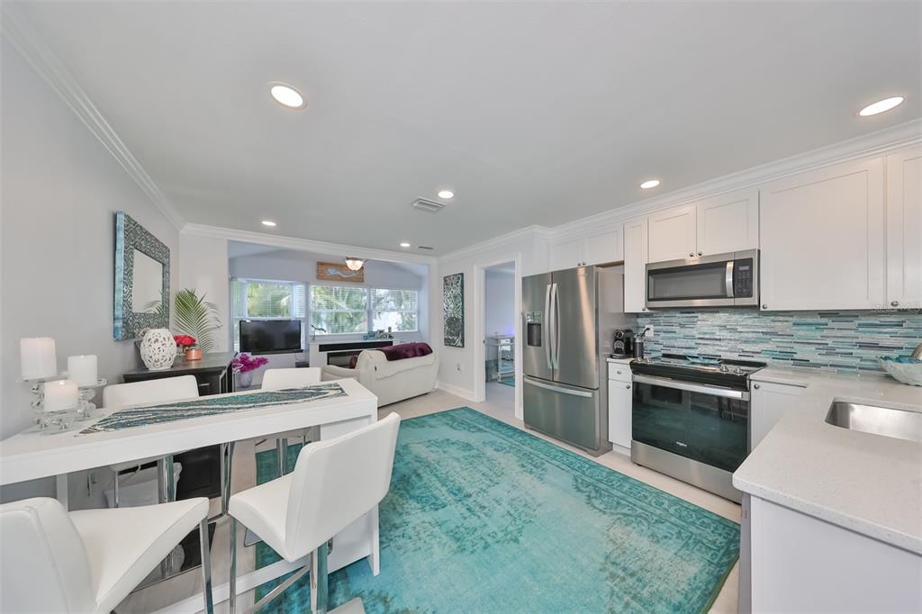 A kitchen and dining area with white cabinets, stainless steel appliances, and a turquoise rug — 13004 BOCA CIEGA AVENUE, MADEIRA BEACH, FL
