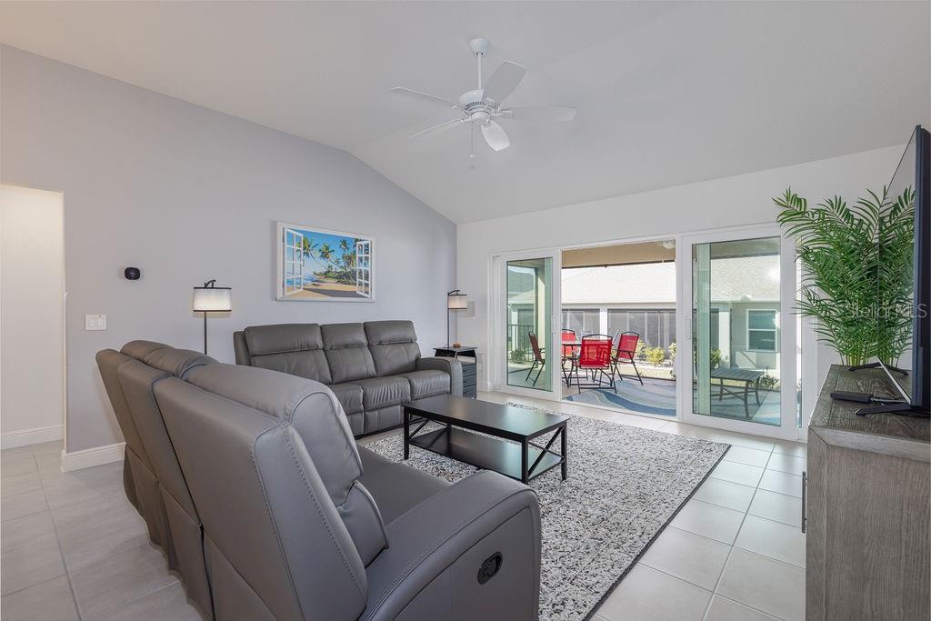 A living room with gray leather furniture, a ceiling fan, and sliding doors to a patio — 2454 YOUNGMANN LOOP, THE VILLAGES, FL