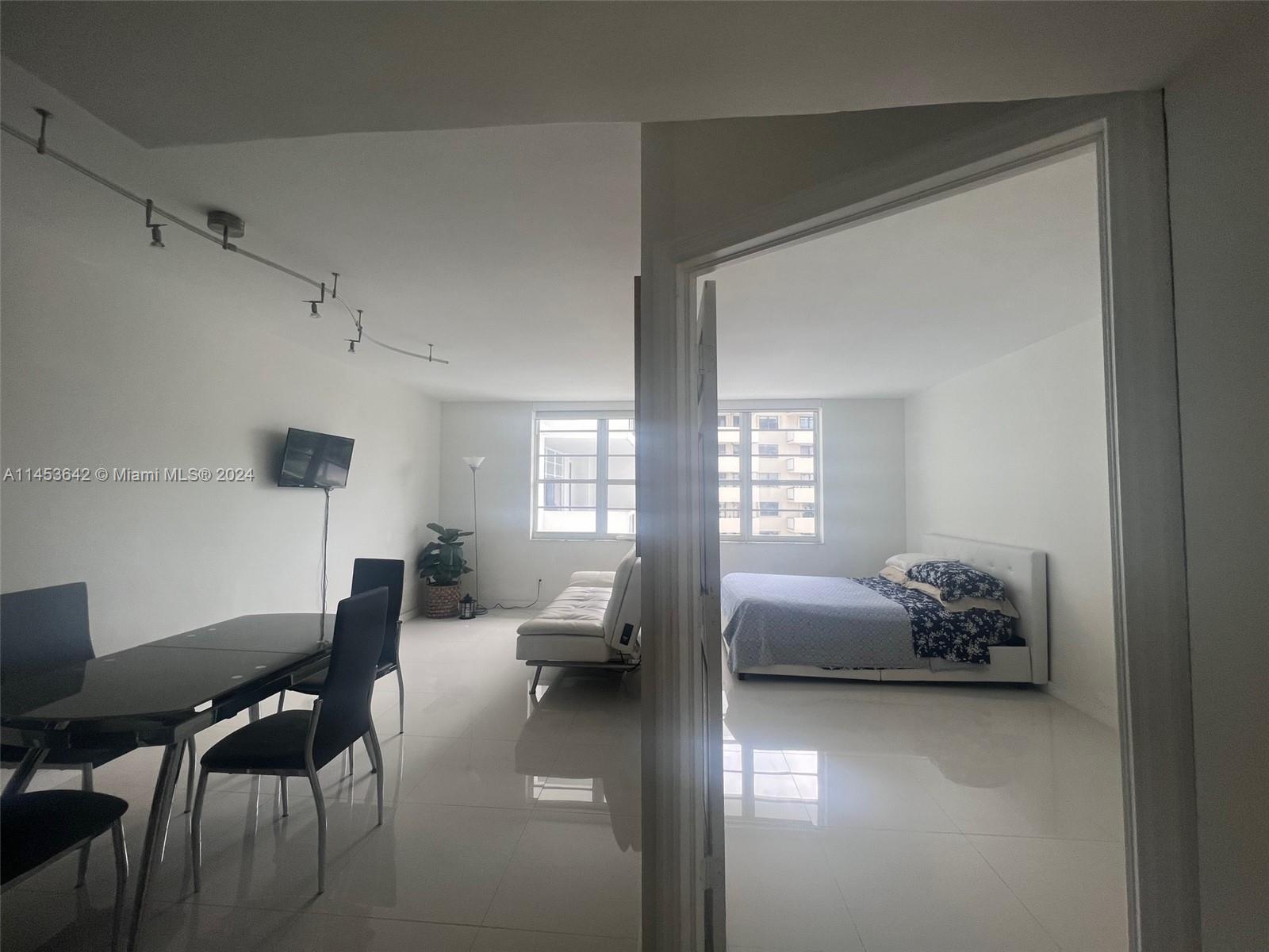 A dining area and bedroom are visible in this apartment with white tile flooring — 100 Lincoln Rd # 501, Miami Beach FL 33139, MIAMI BEACH, FL