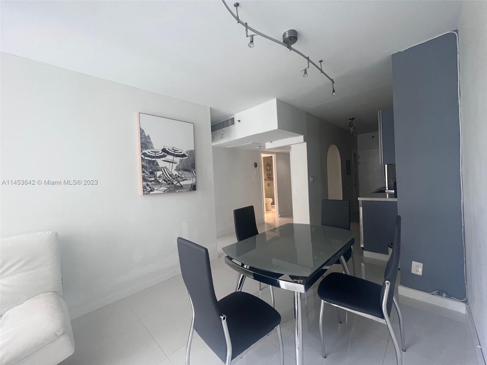 A dining area features a glass table, four black chairs, and a wall-mounted beach print — 100 Lincoln Rd # 501, Miami Beach FL 33139, MIAMI BEACH, FL