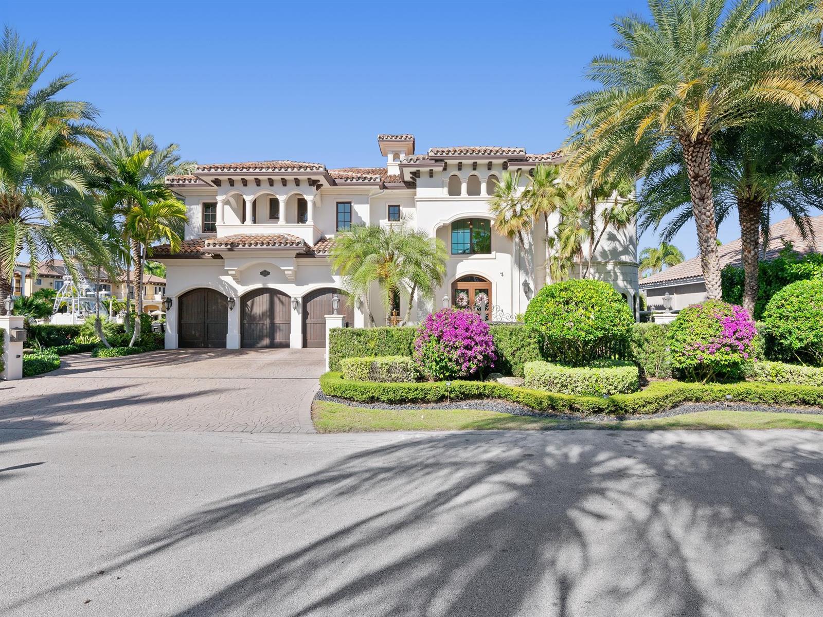 A large Mediterranean-style house with a three-car garage and manicured landscaping under a clear sky — 2319 NE 28th Street, Lighthouse Point FL 33064, LIGHTHOUSE POINT, FL