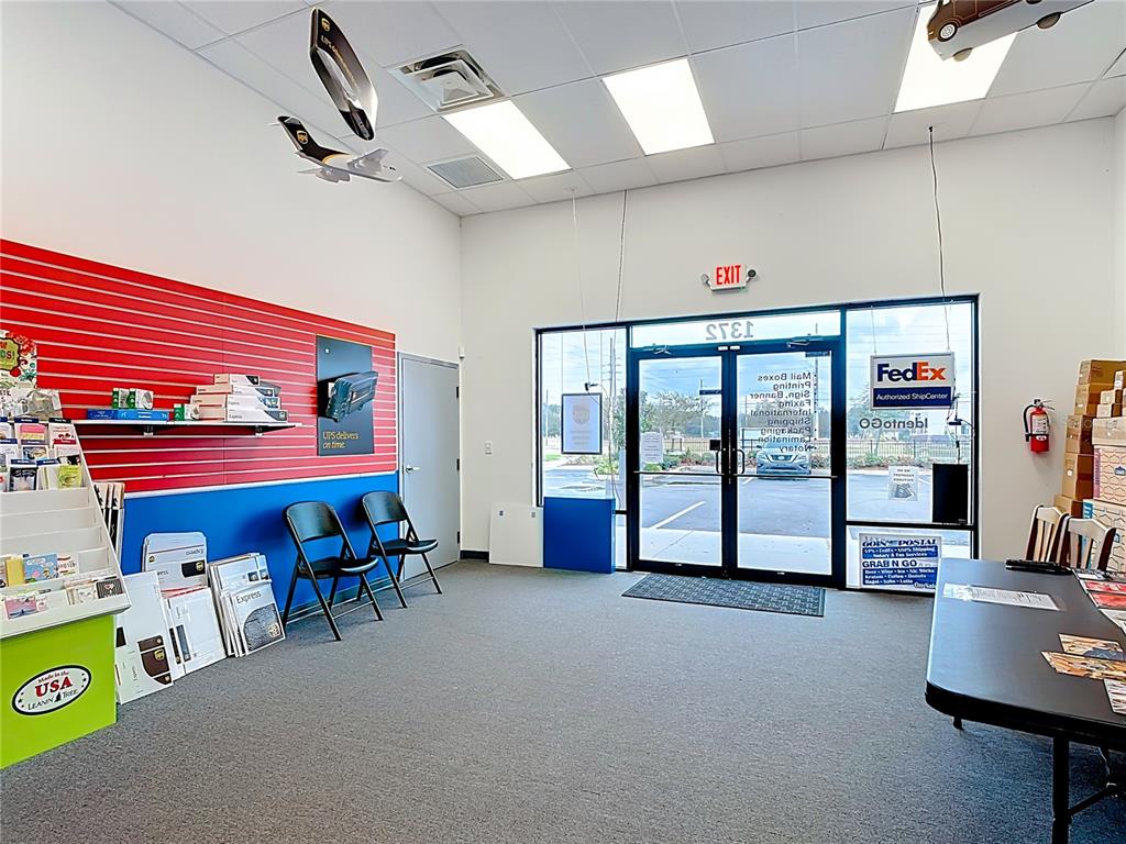 An interior view of a commercial shipping center with a red and blue wall — 1372 S NARCOOSSEE ROAD, ST CLOUD, FL