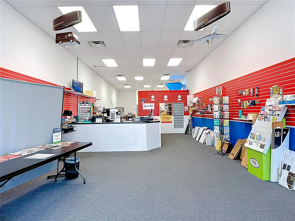 A commercial shipping and retail store interior features a service counter, shelving, and carpeted flooring — 1372 S NARCOOSSEE ROAD, ST CLOUD, FL