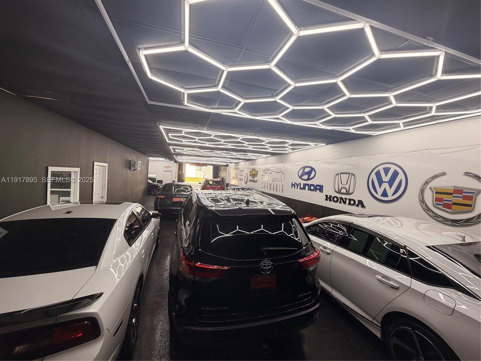 A car dealership garage features a hexagonal LED ceiling light grid and various brand logos — 7298 NW 54th St, Miami FL 33166, MIAMI, FL