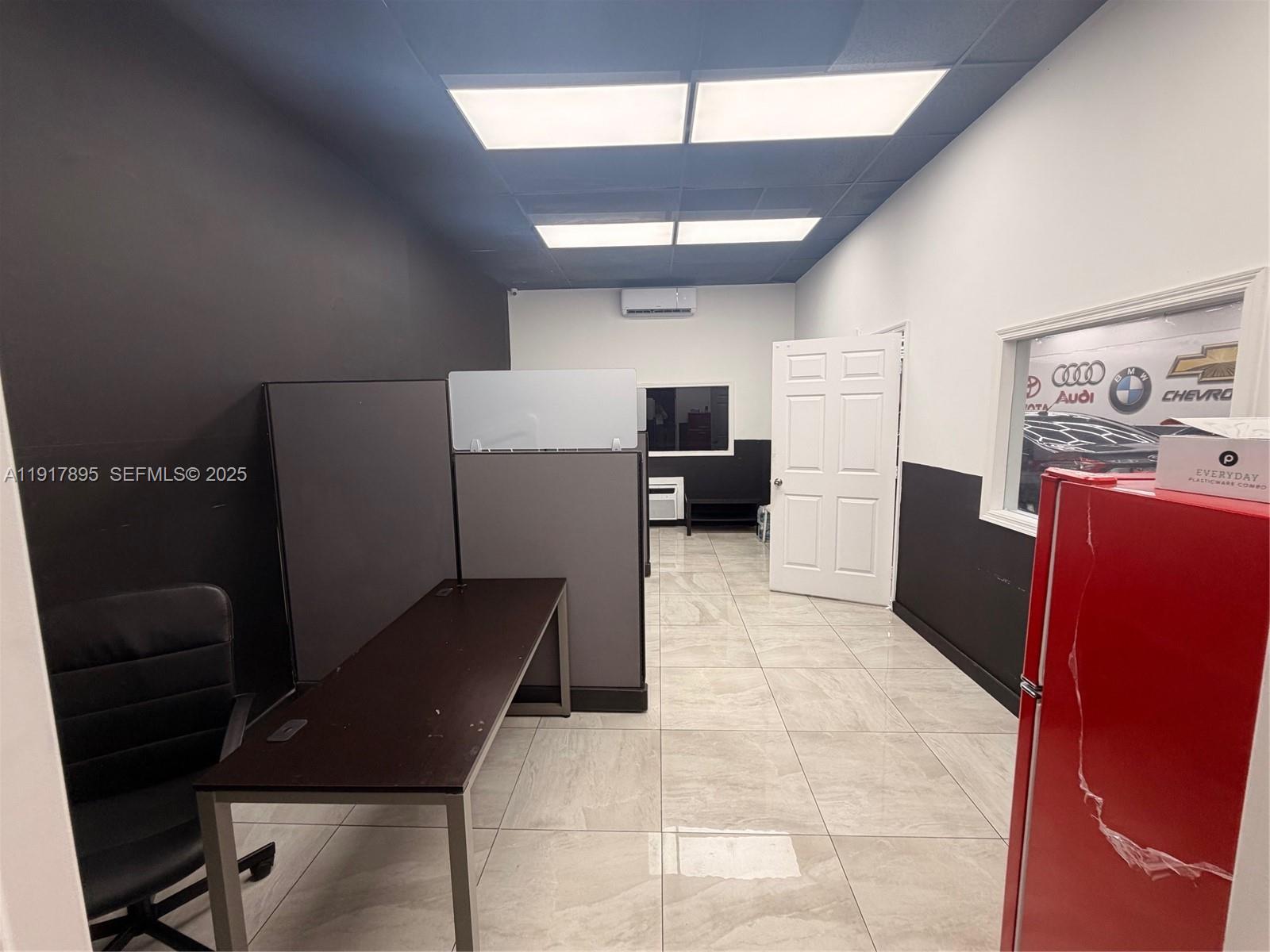 An office space features a dark desk, cubicle partitions, tiled floors, and a red refrigerator — 7298 NW 54th St, Miami FL 33166, MIAMI, FL