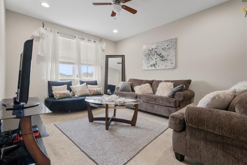A living room features brown sofas, a glass coffee table, and a television on a stand — 2987 BOATING BOULEVARD, KISSIMMEE, FL
