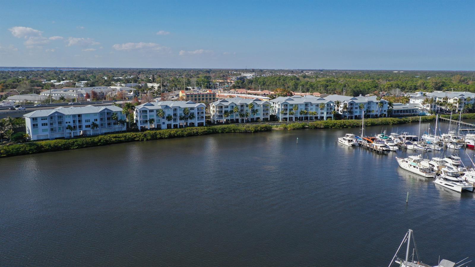 An aerial view shows waterfront apartment buildings alongside a marina filled with docked boats — 975 NW Flagler Avenue # 206, Stuart FL 34994, STUART, FL