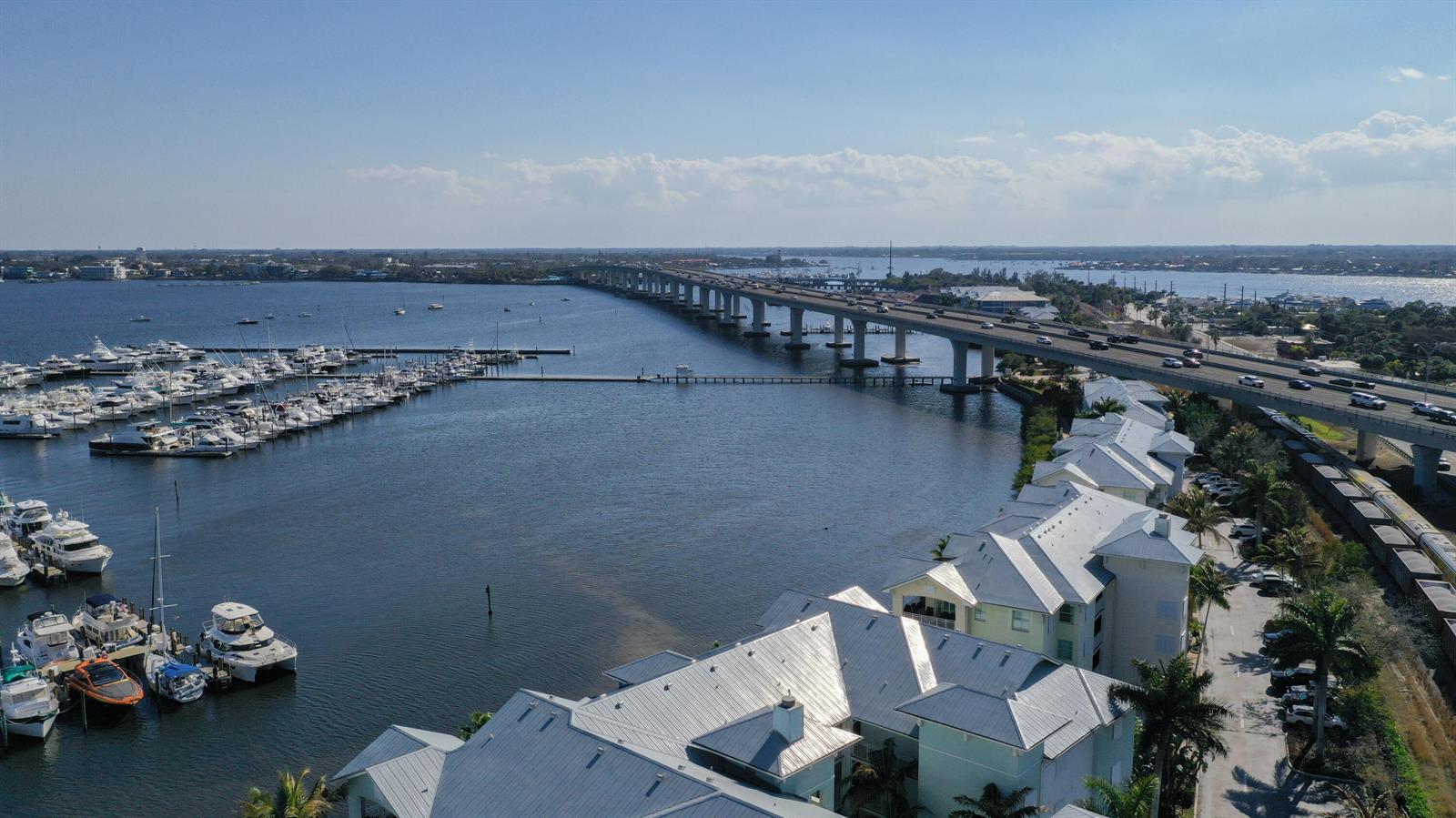 An aerial view shows a marina, a long bridge over water, and waterfront residential buildings — 975 NW Flagler Avenue # 206, Stuart FL 34994, STUART, FL