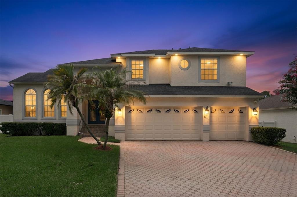 A two-story suburban house with a three-car garage and a paved driveway at dusk — 8355 DIAMOND COVE CIRCLE, ORLANDO, FL