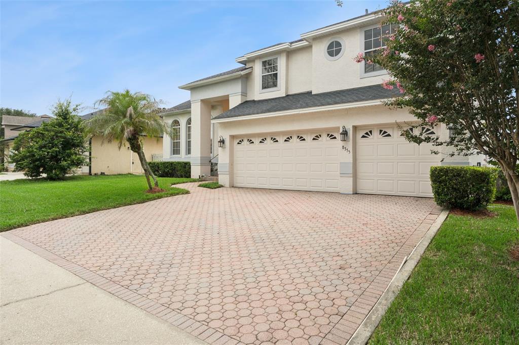 A two-story house with a paved driveway, a three-car garage, and a landscaped front yard — 8355 DIAMOND COVE CIRCLE, ORLANDO, FL