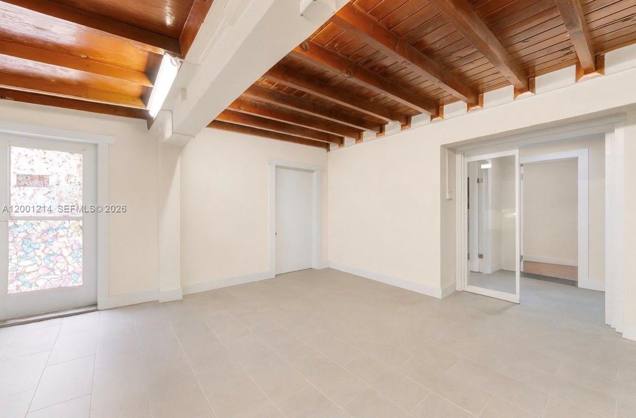 An empty room features white walls, light tile flooring, and an exposed wood beam ceiling — 101875 Overseas Hwy, Key Largo FL 33037, KEY LARGO, FL