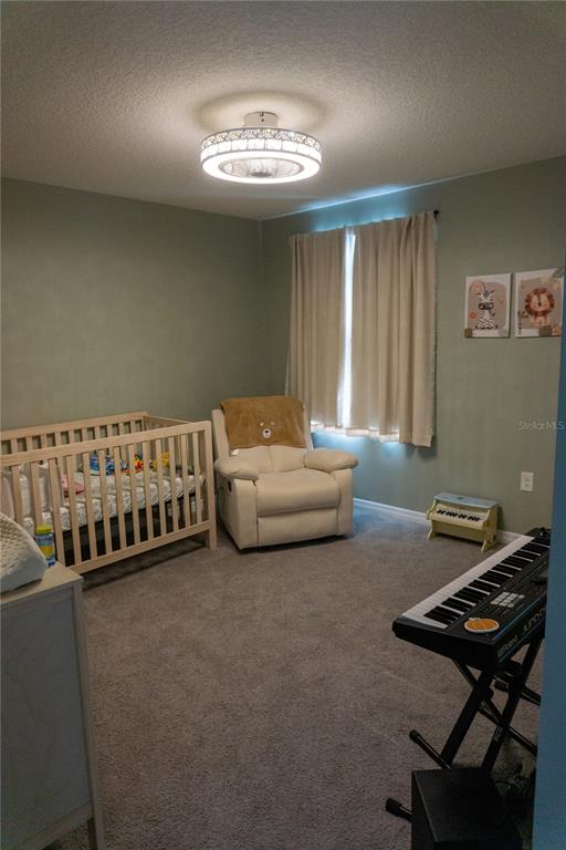 A nursery features a wooden crib, a white recliner, and a keyboard on a stand — 7819 SAIL CLOVER LANE, ZEPHYRHILLS, FL